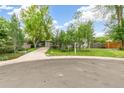 Charming home with a well-manicured front lawn, mature trees, and a long driveway leading to the garage at 4285 Newland St, Wheat Ridge, CO 80033