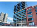 Modern high-rise condo building with brick and glass exterior, showcasing parking and nearby structures at 2020 Arapahoe St # 1070, Denver, CO 80205