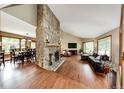 Open-concept living space with hardwood floors, a stone fireplace, and a view of the adjacent dining area at 8788 E Tanglewood Rd, Franktown, CO 80116