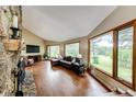 Bright living room featuring hardwood floors, a stone fireplace, and large windows offering scenic views at 8788 E Tanglewood Rd, Franktown, CO 80116