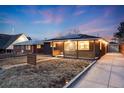 Exterior shot of a cozy home with solar panels, warm lighting, and well-maintained landscaping at twilight at 1742 S Alcott St, Denver, CO 80219
