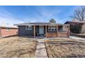 Updated home showcasing solar panels, brick facade, front porch with decorative wood, and walkway at 1742 S Alcott St, Denver, CO 80219