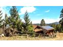 Exterior shot of a mountain home with mature trees, a rustic fence and solar panels at 33121 Lynx Ln, Evergreen, CO 80439