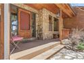 Charming front porch with stone accents, wooden door, and seating area, exuding warmth and character at 33121 Lynx Ln, Evergreen, CO 80439