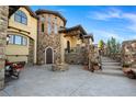 Elegant stone home with arched windows, a cozy outdoor fireplace, and meticulously designed landscaping at 7767 Dante Dr, Littleton, CO 80125