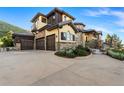 Spacious stucco and stone home boasting a three-car garage and a well-manicured front yard under a blue sky at 7767 Dante Dr, Littleton, CO 80125