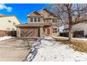 Two-story house with a brown exterior, red door, and attached garage. Snow on the ground at 672 Pitkin Way, Castle Rock, CO 80104