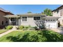 Single-story home with a well manicured lawn, an attached garage, and mature trees in the background at 1627 S Saint Paul St, Denver, CO 80210