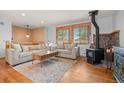 Cozy living room featuring a wood stove, large windows, and comfortable sectional sofa at 37653 Lark Dr, Elizabeth, CO 80107