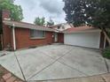 Charming brick home with a spacious concrete driveway and attached two-car garage at 387 Tucson St, Aurora, CO 80011