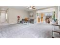 Open-concept living room featuring plush gray carpet and seamless flow into the adjacent dining area at 848 Sagebrush Dr, Brighton, CO 80603