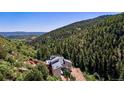 The house is set among a landscape of lush green forest on the side of a mountain at 2602 Hidden Valley Road, Sedalia, CO 80135