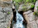 Scenic view of a small waterfall cascading down rocks and lush foliage at 2602 Hidden Valley Road, Sedalia, CO 80135