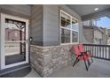 Inviting front porch with stone accents, gray siding, and cozy seating for enjoying the outdoors at 9836 Banner Peak St, Littleton, CO 80125