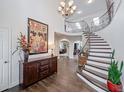 Grand foyer featuring a curved staircase, hardwood floors, elegant chandelier, and a decorative console table at 19080 E Low Cir, Aurora, CO 80015