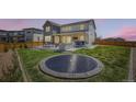 Spacious backyard featuring a trampoline, fire pit, outdoor dining area, and lush green lawn at 6255 Kenzie Cir, Castle Pines, CO 80108