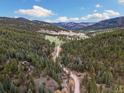 Breathtaking aerial view of property nestled within lush forest landscape in a serene, mountain setting at 7559 S Turkey Creek Rd, Morrison, CO 80465