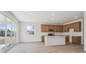 Open-concept kitchen featuring an island, wood cabinetry, and stainless steel appliances with a seamless flow to the living area at 849 Alpine Ridge St, Erie, CO 80516