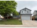 Charming gray two-story home with a basketball hoop, lush tree and well-manicured lawn at 12119 Forest St, Thornton, CO 80241