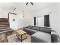 Cozy living room with modern gray sofa, hardwood floors, and staircase access at 12119 Forest St, Thornton, CO 80241
