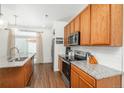 Well-lit kitchen featuring stainless steel appliances, wood cabinetry, and granite countertops at 4431 N Quatar Ct, Aurora, CO 80019