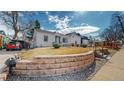 Exterior view featuring a well-manicured lawn, brick retaining wall, and white siding at 4154 Depew St, Denver, CO 80212