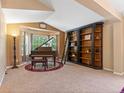 Cozy living room featuring a beautiful bay window, piano, and custom bookshelf at 885 Sage Sparrow Cir, Highlands Ranch, CO 80129