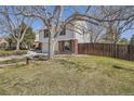 Beautiful home exterior with brick accents and a lush yard, complemented by mature trees and a wood fence at 7998 S Wabash Ct, Centennial, CO 80112