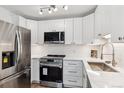 Modern kitchen with white cabinets, stainless steel appliances, and a corner sink at 775 S Alton Way # 2C, Denver, CO 80247