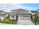 Beautiful two-story home featuring gray siding, stone accents, a three-car garage, and a well-manicured front lawn at 3091 Keepsake Way, Castle Rock, CO 80109
