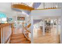 Open foyer with curved staircase, light wood floors, and views into dining room at 6650 Village Rd, Parker, CO 80134