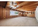 Spacious living room with wood paneling, beamed ceiling, ceiling fan, and large window at 209 S 13Th Ave, Brighton, CO 80601
