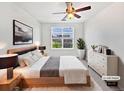 Bright bedroom with a wooden bed frame, ceiling fan, and a large window with neighborhood views at 4100 Albion St # 523, Denver, CO 80216