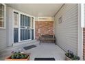 Inviting covered front porch with bench seating and decorative planters and secure storm door at 7664 S Ivanhoe Way, Centennial, CO 80112