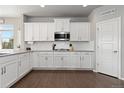 Stylish kitchen featuring white cabinets, stainless steel microwave, and dark hardwood floors, next to a door at 1315 Sidewinder Cir, Castle Rock, CO 80108