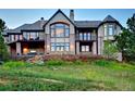 Spacious rear exterior with stone accents, outdoor fireplace, large windows, and grassy yard at 770 International Isle Dr, Castle Rock, CO 80108