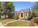 Charming brick home with a well-manicured lawn and inviting front porch seating at 2435 N Irving St, Denver, CO 80211