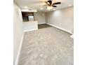 Spacious living room featuring new carpet, adjacent kitchen area, and ceiling fan at 64 Nome Way # C, Aurora, CO 80012