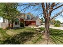 Landscaped front yard of home with mature tree, green grass, and a brick and siding facade at 105 Hawthorn St, Frederick, CO 80530
