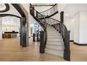 Grand foyer with a curved staircase, wood floors, and arched entryways at 8680 Summerlin Pl, Longmont, CO 80503