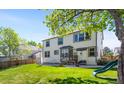 Expansive backyard with a well-maintained lawn, patio area, slide, and mature trees for shade at 19817 E Prentice Ave, Centennial, CO 80015