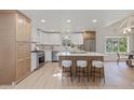 Well-lit kitchen featuring an island, white cabinets, stainless steel appliances, and wood-style flooring at 41 Eagle Dr, Littleton, CO 80123