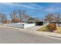 Street view of a quaint home with a carport, complemented by a tidy lawn and a white picket fence at 6660 Locust St, Commerce City, CO 80022