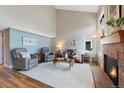 Spacious living room with vaulted ceilings, a brick fireplace, wood floors, and neutral wall colors at 42 Blue Sage, Littleton, CO 80127