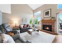 Bright living room with vaulted ceilings, a brick fireplace, large windows, and comfortable seating at 42 Blue Sage, Littleton, CO 80127