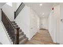 Inviting entryway with hardwood floors, staircase with dark wood railings and white trim at 1376 Lumber Ridge N Cir, Erie, CO 80516