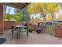 Outdoor patio featuring brick flooring, a table and chairs, grill, and a decorative iron gate at 3434 S Race St, Englewood, CO 80113