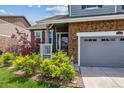 Close-up of the front porch with brick facade, decorative shrubs, and a well-manicured lawn at 25850 E 3Rd Ave, Aurora, CO 80018