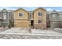 Two-story tan home with dark accents and a two-car garage on a snow dusted front lawn at 4733 S Wenatchee Cir, Aurora, CO 80015