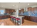 Gourmet kitchen features a large center island with bar seating, custom cabinetry, and stainless steel appliances at 1794 Wright Dr, Erie, CO 80516